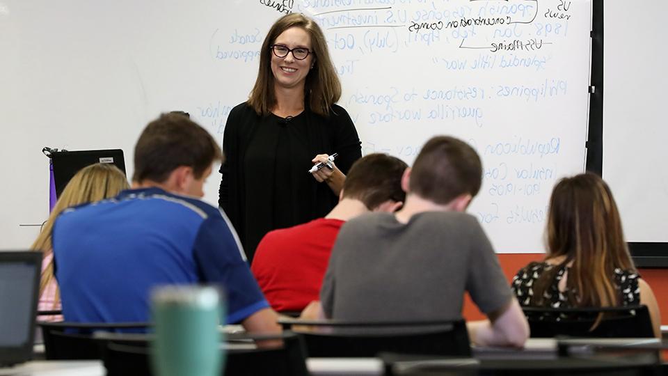 A teacher stands in front of a class of students.